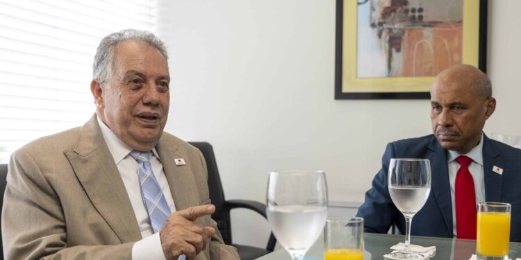 «En la Cruz Roja, somos mucho más que sangre y ambulancias» La institución humanitaria celebra hoy su 99 aniversario con más de 10,000 voluntarios activos y presencia a nivel nacional para responder a desastres y emergencias Claudia FernándezClaudia FernándezClaudia Fernández – Twitter Santo Domingo – abr. 15, 2026 | 12:01 a. m.| 6 min de lectura Compartir»En la Cruz Roja, somos mucho más que sangre y ambulancias»»En la Cruz Roja, somos mucho más que sangre y ambulancias»»En la Cruz Roja, somos mucho más que sangre y ambulancias»CompartirCompartir Expandir imagen»En la Cruz Roja, somos mucho más que sangre y ambulancias» Miguel Sanz Flores y Blaurio Alcántara abogan por mayor participación del sector privado en las labores de la Cruz Roja Dominicana. (DIARIO LIBRE/NELSON PULIDO) ¿Quieres resumir esta noticia?Clic aquí La Cruz Roja Dominicana conmemora hoy, 15 de abril, sus 99 años de fundación, fungiendo como una de las instituciones humanitarias más importantes del país, con presencia en todo el territorio nacional y un rol clave en la atención de emergencias, la prevención de riesgos y la asistencia social. Fundada el 15 de abril de 1927 por iniciativa de la entonces primera dama, Trina de Moya, junto a un grupo de médicos, la institución tuvo su primera gran prueba apenas tres años después, tras el devastador ciclón de San Zenón en 1930. A partir de ese momento, comenzó a consolidarse como un actor clave en la respuesta a desastres en el país. Aunque tradicionalmente la población asocia la Cruz Roja con la donación de sangre y el servicio de ambulancias, sus autoridades aseguran que su labor es mucho más amplia. «La mayoría de las personas cuando hablan de Cruz Roja piensan en sangre y ambulancia, pero, somos mucho más que eso. El primer pilar que tiene la Cruz Roja es justamente la prevención: prevención de accidentes, prevención familiar, llamar a la prudencia», afirmó su director, Blaurio Alcántara. Actualmente, la institución desarrolla programas de formación en primeros auxilios, salud comunitaria, apoyo psicosocial y preparación ante emergencias, además de impulsar sistemas de alerta temprana en provincias como San Juan y La Altagracia para monitorear fenómenos climáticos, un programa de gallinas ponedoras, producción y panaderías para madres solteras en Elías Piña y Pedernales y sus tradicionales operativos por Semana Santa y Navidad. Email icon Recibe las principales noticias del día en tu bandeja de correo con nuestro newsletter Lo que tienes que saber. Introduce tu email Con más de 10,000 voluntarios activos y 156 filiales en todo el país, la Cruz Roja Dominicana se caracteriza por su rápida capacidad de respuesta ante emergencias. «Somos los primeros en llegar y los últimos en salir», aseguró Alcántara, al recordar la reciente intervención tras las lluvias del pasado 8 de abril, donde los equipos comenzaron a operar desde la madrugada. Estos voluntarios, capacitados en distintas áreas, realizan evaluaciones de daños, levantamientos de información y mapeo, ubicación de albergues y distribución de ayuda humanitaria, incluyendo kits de higiene, alimentos, herramientas, acceso a agua potable mediante plantas móviles y un almacén de apoyo logístico para dar soporte hasta a cinco mil familias. «A las personas hay que enseñarles que no pueden vivir haciendo casas a orillas de ríos y cañadas y las alertas rojas deben respetarlas», subrayó. La Cruz Roja también forma parte del sistema nacional de respuesta a emergencias, siendo la única entidad privada que participa en el Centro de Operaciones de Emergencias (COE). «Somos la única institución de derecho privado que participa en el COE, somos la única institución auxiliar de los poderes del Estado en materia humanitaria», explicó su presidente, Miguel Sanz Flores. 153 ambulancias Además, es uno de los principales proveedores del sistema 9-1-1, con una flota de 153 ambulancias equipadas y operadas por personal propio. «El servicio que prestamos lo cubre la Cruz Roja, suministramos no solamente la ambulancia, sino todo lo que tiene que ver con los equipamientos, el personal, mantenimiento, combustible» Miguel Sanz Flores Presidente de la Cruz Roja Dominicana “ Sin embargo, advirtió que este servicio opera prácticamente subsidiado, debido a los altos costos operativos y el limitado apoyo económico, en especial, del sector privado. «La Cruz Roja recibe, desde hace más o menos treinta años, tres millones y pico de pesos del Estado Dominicano», indicaron, al tiempo que explicaron que solo el banco de sangre requiere alrededor de ocho millones de pesos al mes para operar. RELACIONADAS Cruz Roja dispone de almacén humanitario para servicios de emergencia tras fenómenos atmosféricos Salud Cruz Roja dispone de almacén humanitario para servicios de emergencia tras fenómenos atmosféricos Cruz Roja Dominicana impulsa acciones para garantizar acceso a agua segura Medio Ambiente Cruz Roja Dominicana impulsa acciones para garantizar acceso a agua segura Más de 10 mil voluntarios de la Cruz Roja participarán en operativo de Semana Santa Nacional Más de 10 mil voluntarios de la Cruz Roja participarán en operativo de Semana Santa Sangre segura En julio de 1949, la Cruz Roja fundó el primer banco de sangre en el país, de ahí la asociación como proveedor del componente biológico. Para que una pinta sea segura, debe somertese a unos 14 o 15 análisis, incluyendo VIH y hepatitis. Sanz recordó que la sangre O+ es la más frecuente, mientras que las de factor negativo, especialmente la O- y la A-, son más escasas. El tipo B+ también puede presentar escasez. Actualmente, la Cruz Roja funciona en 191 países alrededor del mundo. El desafío de la donación de sangre en nuestro país De acuerdo con Sanz y Alcántara, uno de los principales retos que enfrenta la institución sigue siendo la falta de donación voluntaria de sangre. «Nosotros seguimos más o menos en lo mismo», reconoció su presidente, al señalar que apenas entre 1.5 % y 1.6 % de la población dona sangre, muy por debajo del 5 % recomendado internacionalmente. El 90 % de esa sangre recibida es por reposición, es decir, cuando un familiar necesita sangre, lo que limita la disponibilidad en situaciones de emergencia. «Solo sabemos la importancia de la sangre cuando tenemos una emergencia», resaltó. Diariamente, la Cruz Roja procesa unas 200 pintas. «El tema de sangre es de política pública. La sangre no se hace en laboratorio, se requiere haber conciencia de donar y para lograr eso tenemos que asumir esto como un tema país», enfatizó el director. Para enfrentar esta situación, la Cruz Roja ha implementado un banco móvil de sangre y promueve alianzas con empresas e instituciones para fomentar la donación voluntaria desde el bachillerato. «No importa si usted vive en una torre o vive en una cañada, puede necesitar de las acciones de la Cruz Roja. Si no hay donaciones, si no hay cultura de donar, no importa que haya hemocentro, no es cuestión de edificios», destacó Alcántara. «Nuestra rentabilidad es la social. Es decir, ¿cuántas personas nosotros hemos atendido en un año? No repartimos dividendos, no perseguimos lucros», intervino Sanz. Llamado a las ARS Los directivos de la Cruz Roja hicieron un llamado a las Administradoras de Riesgos de Salud (ARS) para que incluyan el tamizaje de la sangre dentro de sus planes de cobertura. «No se justifica que las demás ARS no tengan en su catálogo la cobertura de sangre, solo Senasa. No vendemos sangre, cobramos la cuota de recuperación por la tamización, unos 4,000 pesos», dijo Blaurio Alcántara.